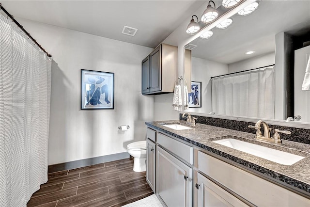full bath with wood finish floors, toilet, baseboards, and double vanity