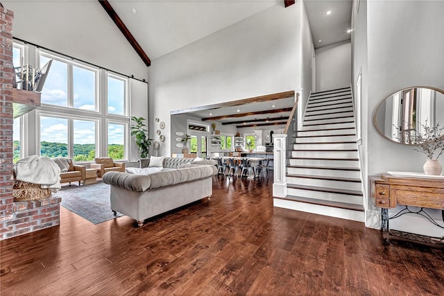 living area featuring high vaulted ceiling, dark wood finished floors, beam ceiling, and stairway
