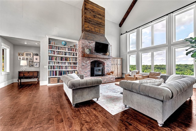 living room featuring beam ceiling, dark hardwood / wood-style flooring, brick wall, a fireplace, and high vaulted ceiling