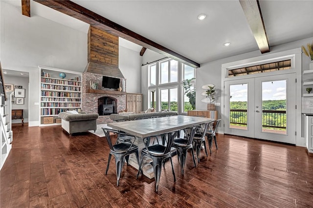 dining area featuring beam ceiling, french doors, a brick fireplace, dark wood finished floors, and baseboards
