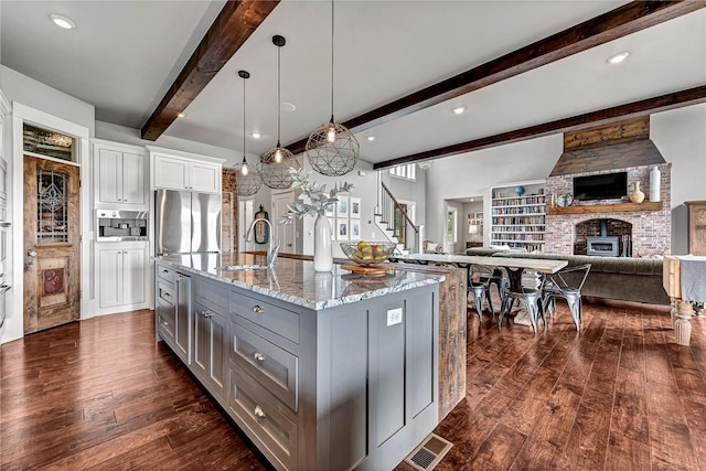 kitchen featuring gray cabinetry, a sink, light stone countertops, dark wood-type flooring, and a fireplace