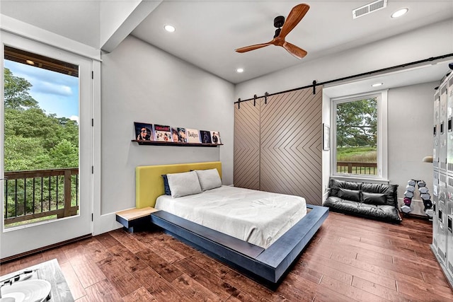 bedroom featuring a barn door, hardwood / wood-style flooring, recessed lighting, access to outside, and ceiling fan
