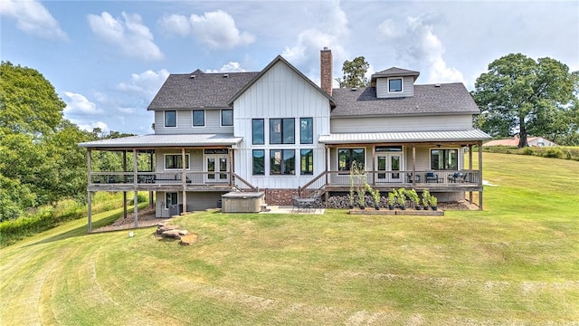 back of property with a hot tub, a deck, a chimney, a lawn, and board and batten siding