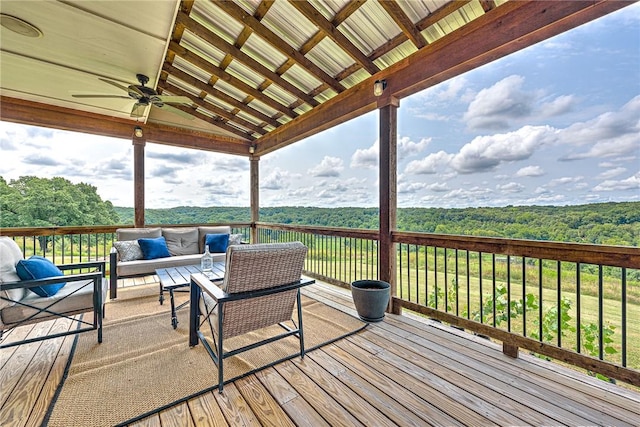 wooden terrace featuring ceiling fan, outdoor lounge area, and a wooded view