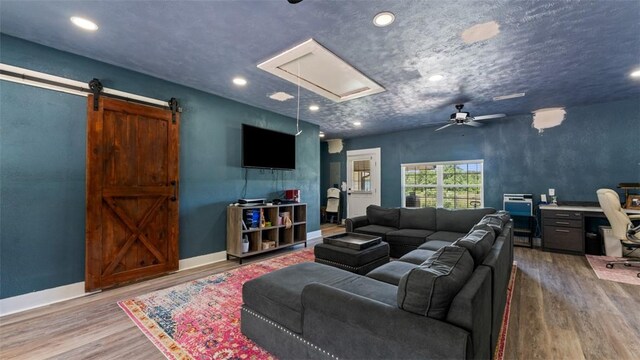 living room with ceiling fan, hardwood / wood-style flooring, and a barn door