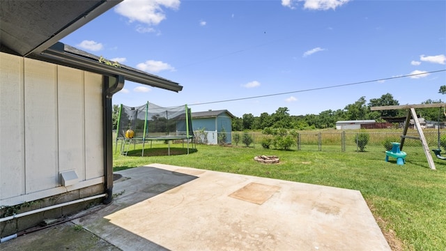 view of yard with a fire pit, a trampoline, and a patio area