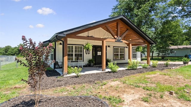 back of property featuring covered porch and a yard