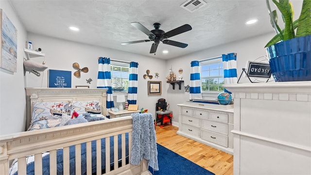 bedroom featuring multiple windows, ceiling fan, and light wood-type flooring