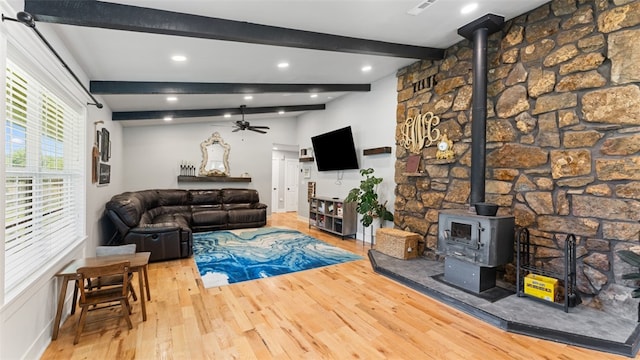 living room featuring a wood stove, wood-type flooring, lofted ceiling with beams, and ceiling fan