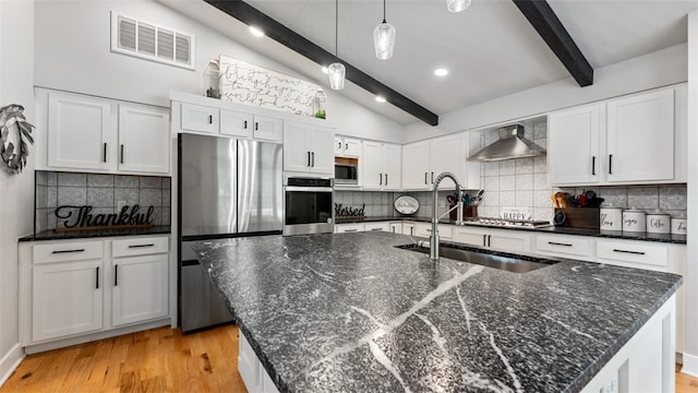 kitchen featuring light hardwood / wood-style flooring, vaulted ceiling with beams, backsplash, appliances with stainless steel finishes, and wall chimney exhaust hood