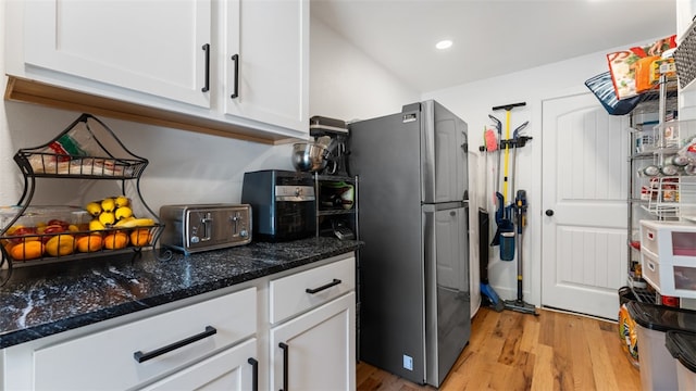 kitchen with white cabinetry, stainless steel fridge, dark stone countertops, and light hardwood / wood-style flooring