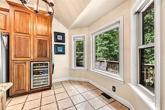 kitchen with vaulted ceiling, a notable chandelier, light tile patterned floors, and wine cooler