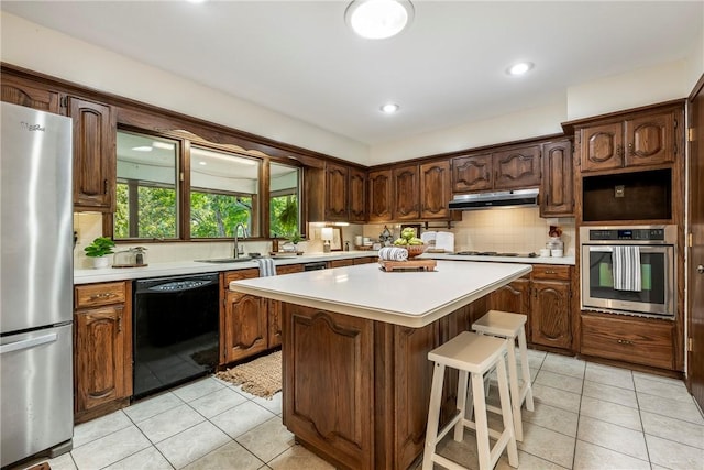 kitchen featuring a kitchen breakfast bar, sink, appliances with stainless steel finishes, tasteful backsplash, and a kitchen island