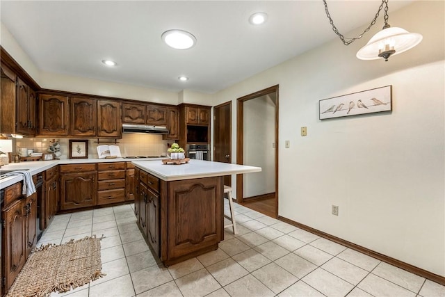 kitchen featuring backsplash, oven, pendant lighting, dark brown cabinets, and a kitchen island