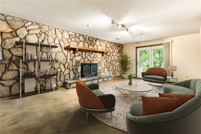 living room featuring a fireplace, track lighting, and a textured ceiling