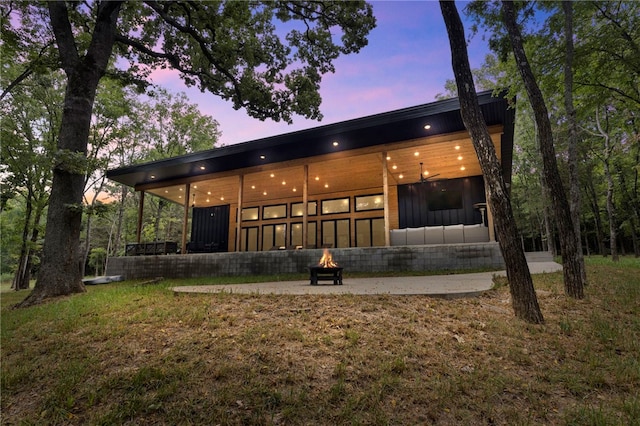 back house at dusk featuring a lawn