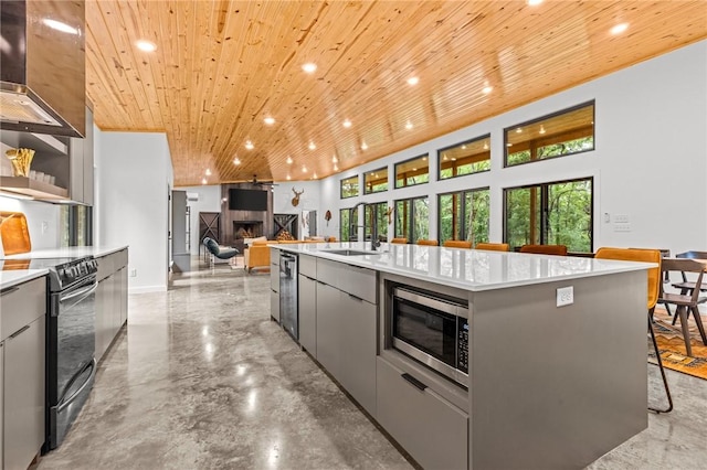 kitchen with sink, gray cabinets, appliances with stainless steel finishes, an island with sink, and wooden ceiling