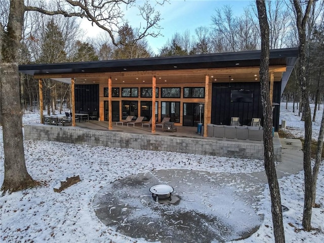 snow covered back of property with a patio