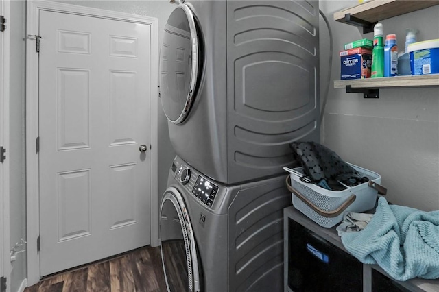 clothes washing area with stacked washing maching and dryer and dark hardwood / wood-style flooring