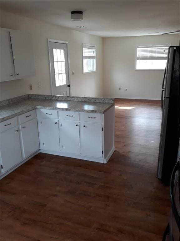 kitchen featuring stainless steel refrigerator, a wealth of natural light, white cabinetry, and dark wood-type flooring