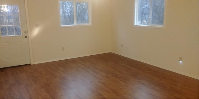 spare room with a wealth of natural light and dark hardwood / wood-style flooring