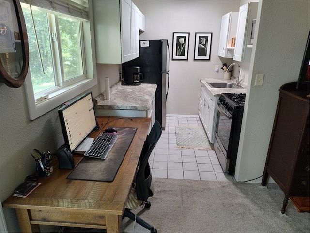 kitchen with light tile patterned floors, white cabinetry, stainless steel gas range oven, and sink