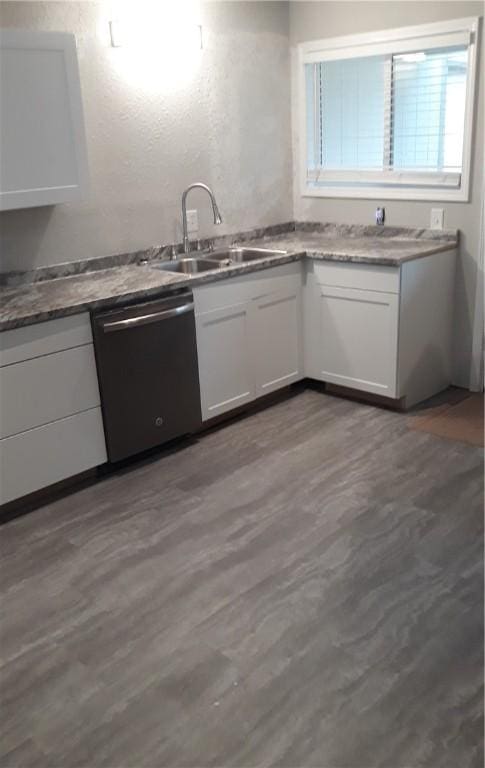 kitchen with white cabinetry, sink, stainless steel dishwasher, and hardwood / wood-style flooring