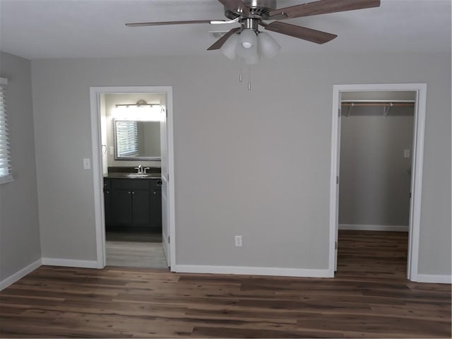 unfurnished bedroom featuring ceiling fan, dark hardwood / wood-style flooring, connected bathroom, and a closet