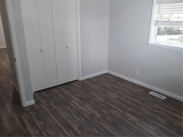 unfurnished bedroom featuring a closet and dark wood-type flooring