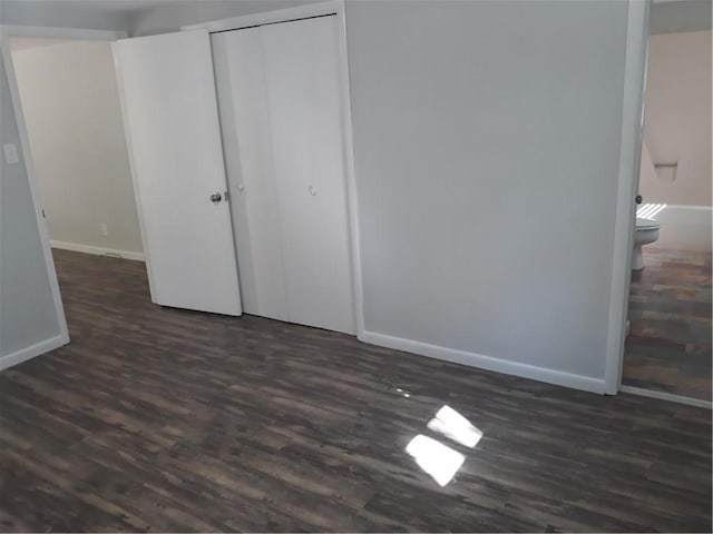 unfurnished bedroom featuring a closet, dark hardwood / wood-style flooring, and ensuite bath