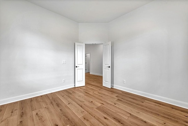 unfurnished room with baseboards and light wood-type flooring