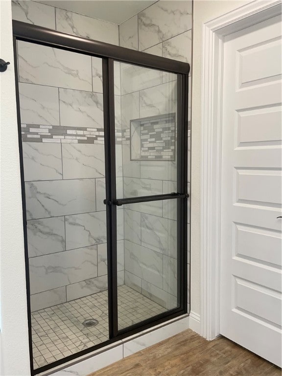 bathroom featuring a shower with shower door and hardwood / wood-style flooring