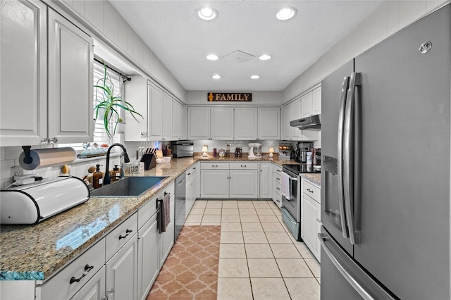 kitchen featuring stainless steel appliances, sink, light tile patterned floors, stone counters, and white cabinetry