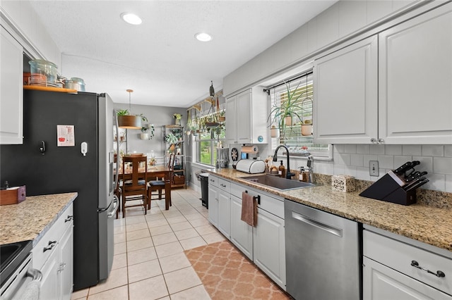 kitchen with white cabinets, sink, stainless steel appliances, and hanging light fixtures