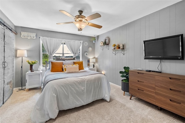 bedroom with light colored carpet, ceiling fan, and wood walls