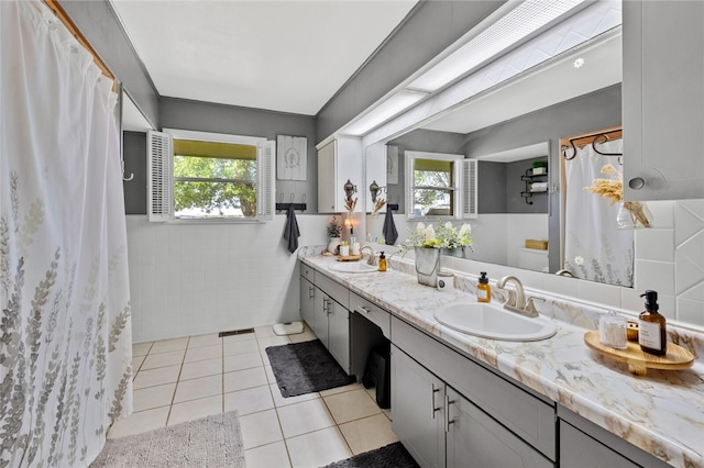 bathroom featuring vanity, tile patterned floors, tile walls, and a healthy amount of sunlight