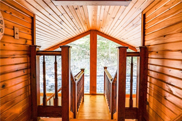 hallway featuring light wood-type flooring, wooden walls, wood ceiling, and vaulted ceiling