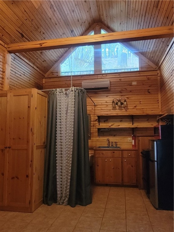 interior space featuring vaulted ceiling with beams, wood walls, light tile patterned floors, and stainless steel fridge