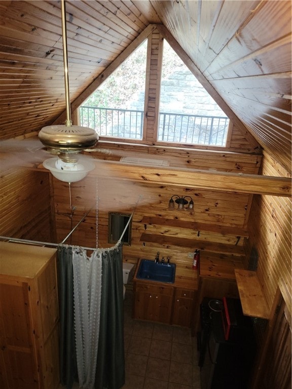 kitchen featuring sink, wood walls, vaulted ceiling, and tile patterned flooring