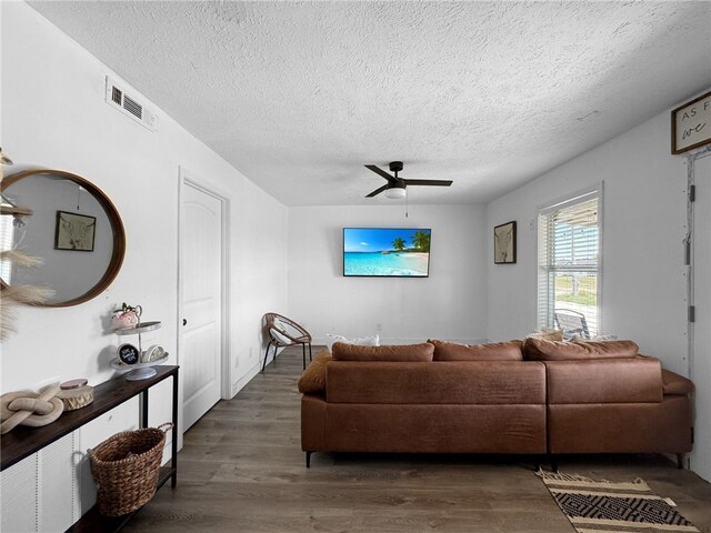 living room featuring ceiling fan, dark hardwood / wood-style flooring, and a textured ceiling