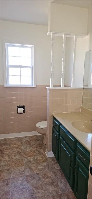 bathroom with vanity, toilet, and tile walls