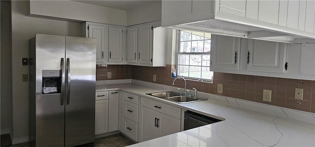 kitchen with appliances with stainless steel finishes, tasteful backsplash, light stone counters, sink, and white cabinets