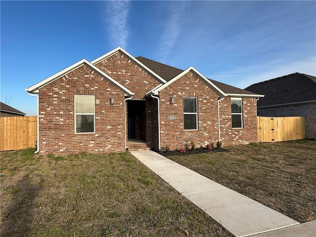 single story home with brick siding, a gate, a front yard, and fence