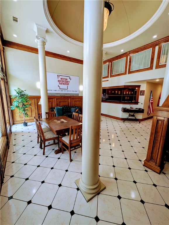 dining area with decorative columns, light tile patterned floors, and a tray ceiling