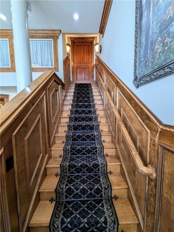 staircase with decorative columns and crown molding