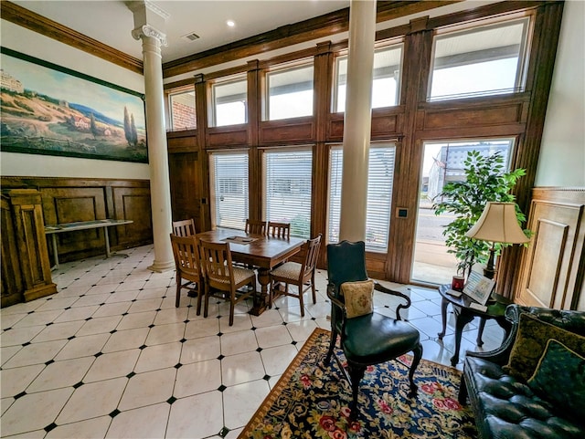 tiled dining area with decorative columns, a high ceiling, and ornamental molding