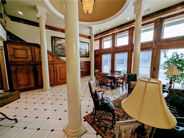 interior space with decorative columns, a raised ceiling, a towering ceiling, and crown molding