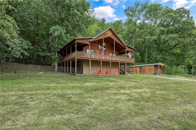 rear view of house featuring a deck, an outdoor structure, and a lawn