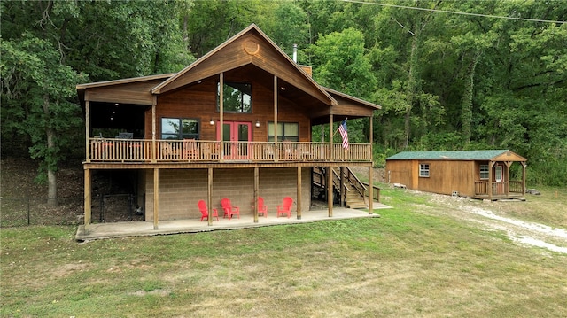 rear view of house featuring a lawn, an outdoor structure, a patio, and a wooden deck