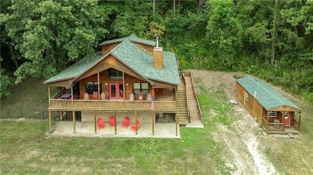 exterior space with a lawn, fence, an outbuilding, a wooden deck, and stairs